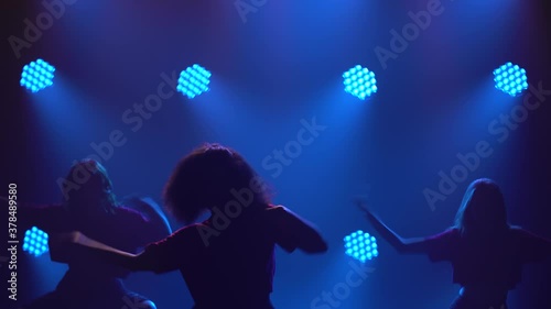Three adorable girls are actively dancing jazz funk in the spotlight. Silhouettes of dancers close up. photo