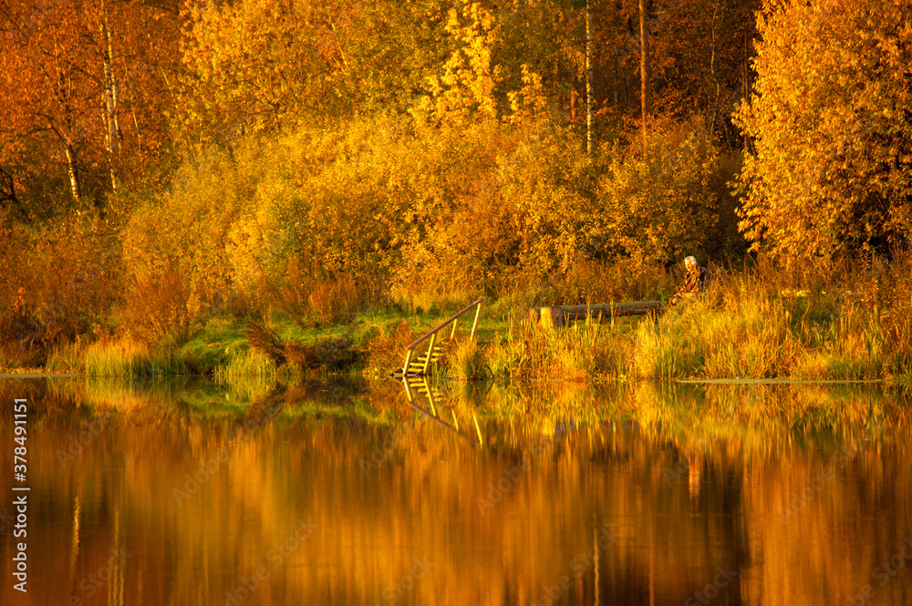 Autumn bright forest reflected in water of lake. Colorful autumn morning landscape. Concepts: season, peaceful, idyllic