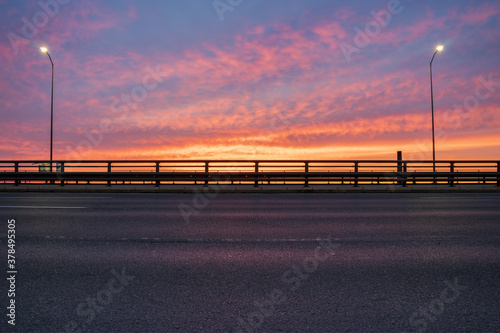 Fototapeta Naklejka Na Ścianę i Meble -  express road leading through the city during sunrise, perfect as a backplate for rendering e.g. cars