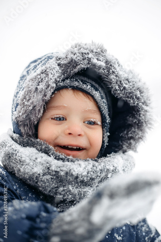 Image of smiling baby boy in a warm white snow suit.