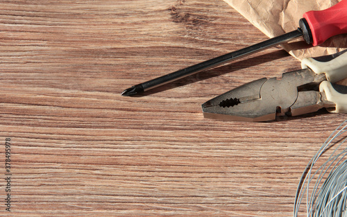 Old tools on a wooden background. Pliers, screwdriver and wire on a wooden background.