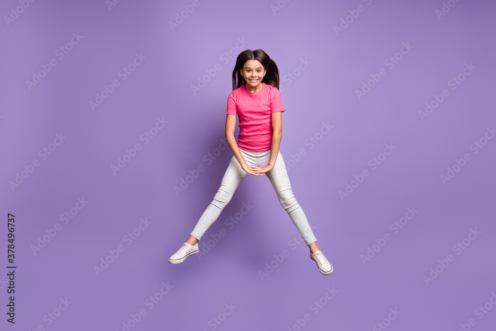 Full length body size photo of jumping high schoolgirl with long brunette hair playing smiling isolated on purple color background