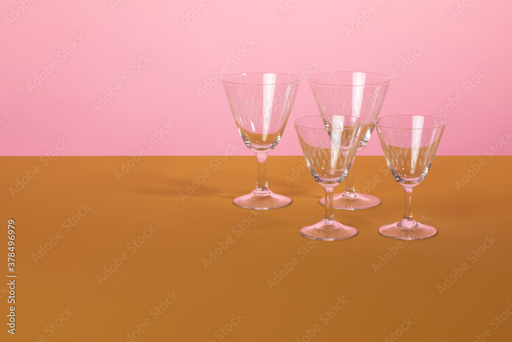 Set of classsic martini cocktail glasses standing on a brown surface and a pink colored background. Clean minimalistic elegant style
