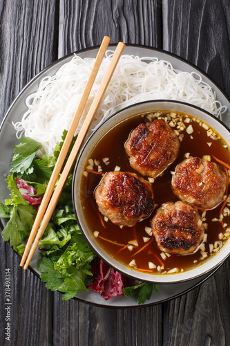 Bun cha is a Vietnamese dish of grilled pork, noodle and herb closeup in the plate on the table. Vertical top view from above