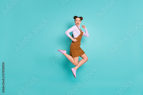 Fototapeta Naklejka Na Ścianę i Meble -  Full length profile photo of glad childish two buns hairstyle lady jump triumph arms fists wear trendy violet footwear sweater autumn brown short dress isolated turquoise color background