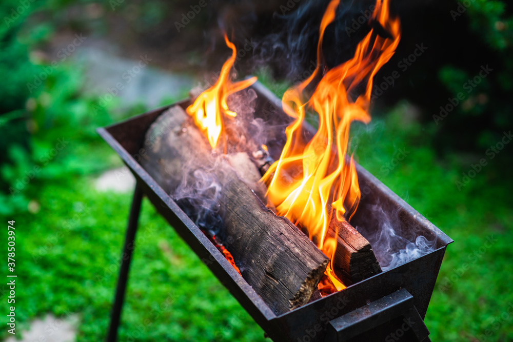 Old braizer with burning firewood on the backyard. Selective focus. Shallow depth of field. Old braizer with burning firewood on the backyard. Selective focus. Shallow depth of field.
