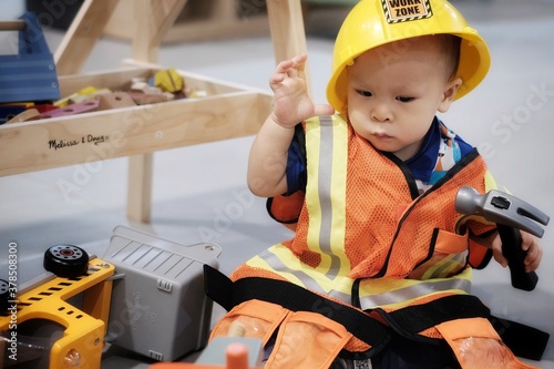 little boy in an engineer uniform is playing with toys.