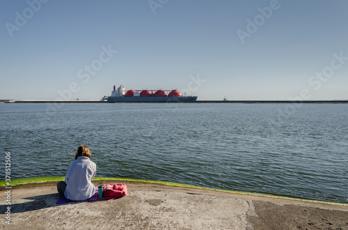 LNG TANKER - Ship on the horizon and a girl on the breakwater