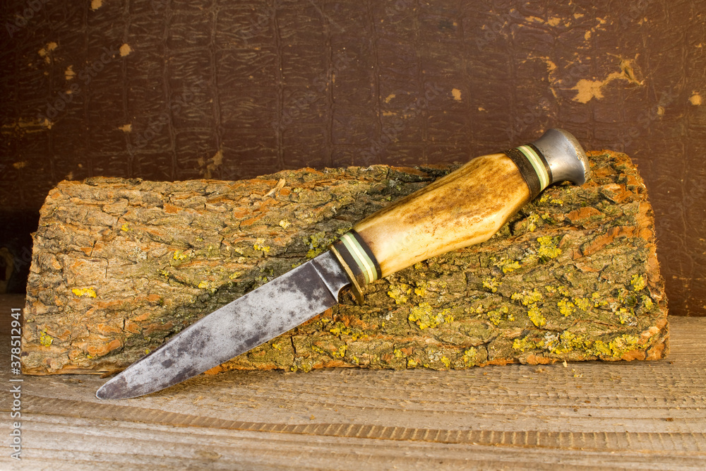 An old hunting knife lies on a piece of wood