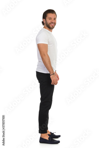Casual Man Is Standing Relaxed And Looking At Camera. Side View.