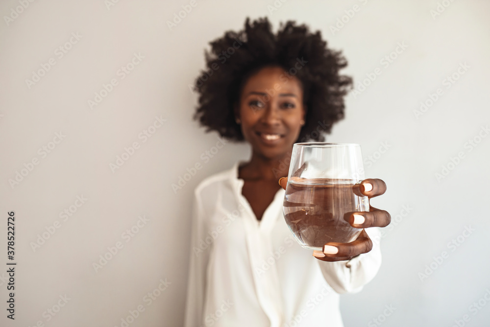 African-American Woman holding glass of water. Happy beautiful young woman holding drinking water glass in her hand. Health care concept. Health trend African-American Woman holding glass of water. Happy beautiful young woman holding drinking water glass in her hand. Health care concept. Health trend