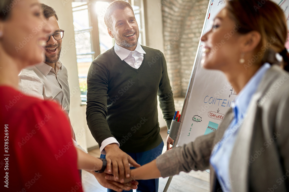Fototapeta premium Happy business team gathering hands in unity after successful presentation.