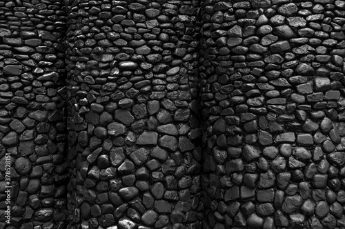 Dark wall of sea pebbles. construction and renovation theme  in curve shape for decoration.