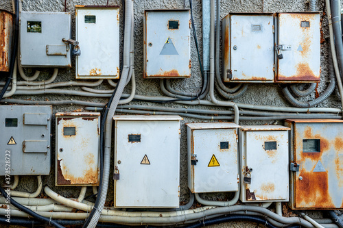Old rusty metal electrical boxes with wires on the wall of an electrical distribution substation