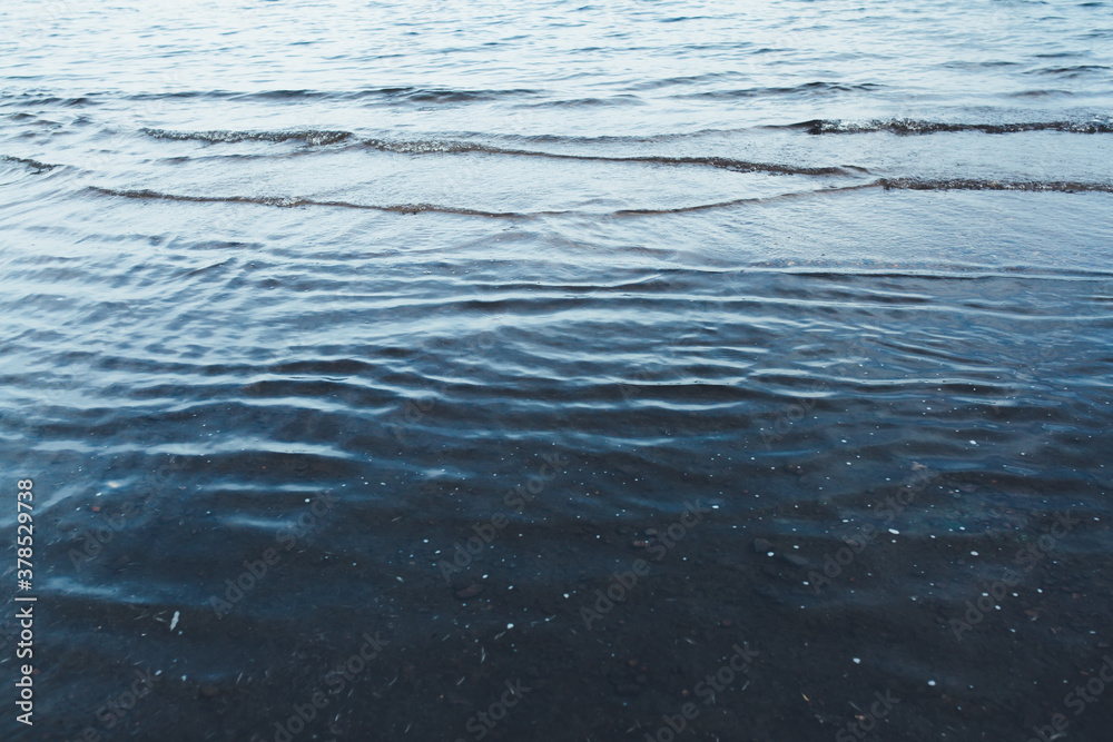 Close-up of water texture, smooth blue waves of water on the shore beach, color landscape photo of water Close-up of water texture, smooth blue waves of water on the shore beach, color landscape photo of water