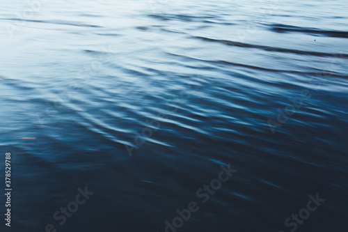 Close-up of water texture, smooth blue waves of water on the shore beach, color landscape photo of water 