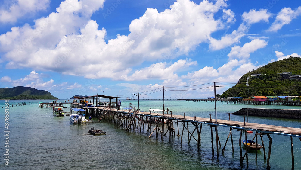 Seascape view. Many speed boat parked at port with wooden bridge among the sea and blue sky and white cloud background in Samaesarn beach, Chon Buri, Thailand. Clear water, beautiful coral. Landscape