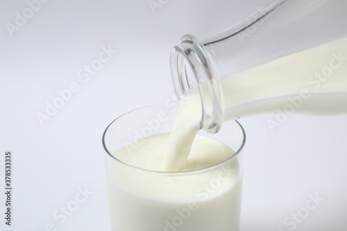 Pouring milk into glass on white background, closeup