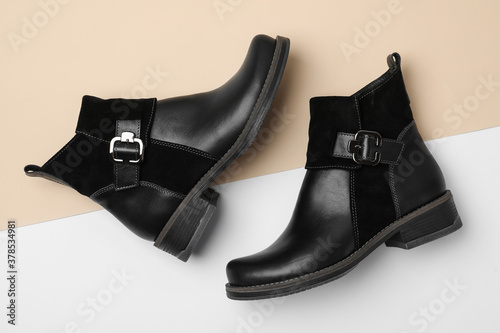 Stylish black female boots on color background, flat lay photo