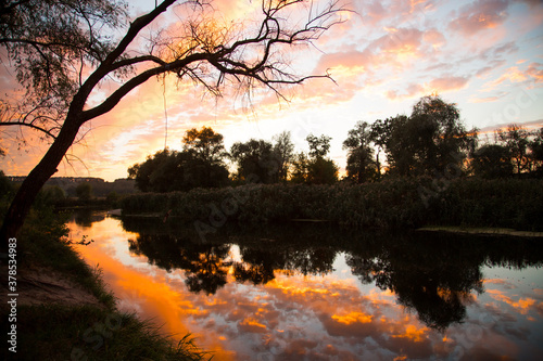 Incredibly beautiful sunset on the river. Reflection of orange-red clouds in the river. Play of colors. Untouched nature. Transparent living water. Seversky Donets River in Ukraine