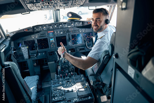 Handsome man in uniform showing like in the cabin of aircraft photo