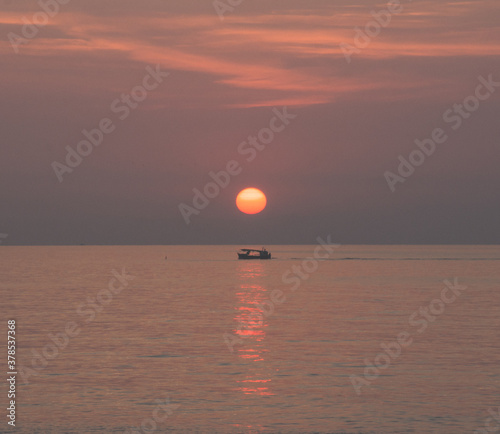 Barca en el mar debajo del sol en el amanecer