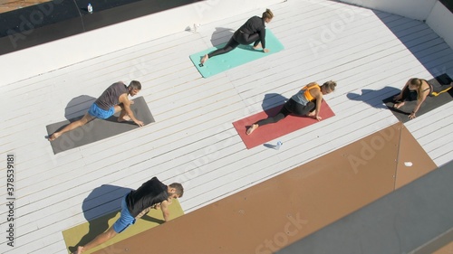 Group of adults are waiting for the start of yoga training on the roof of the house. Outdoor sports. Many people do yoga exercises. Meditation and wellness lifestyle concept
