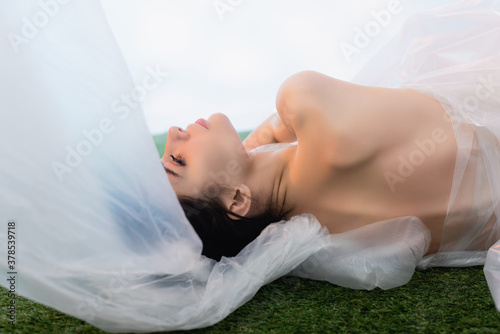 young model wrapped in polyethylene lying on white  ecology concept