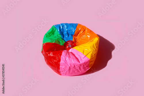 Photos Imagen de balon de playa desinflado con rayas de colores sobre fondo rosa pastel