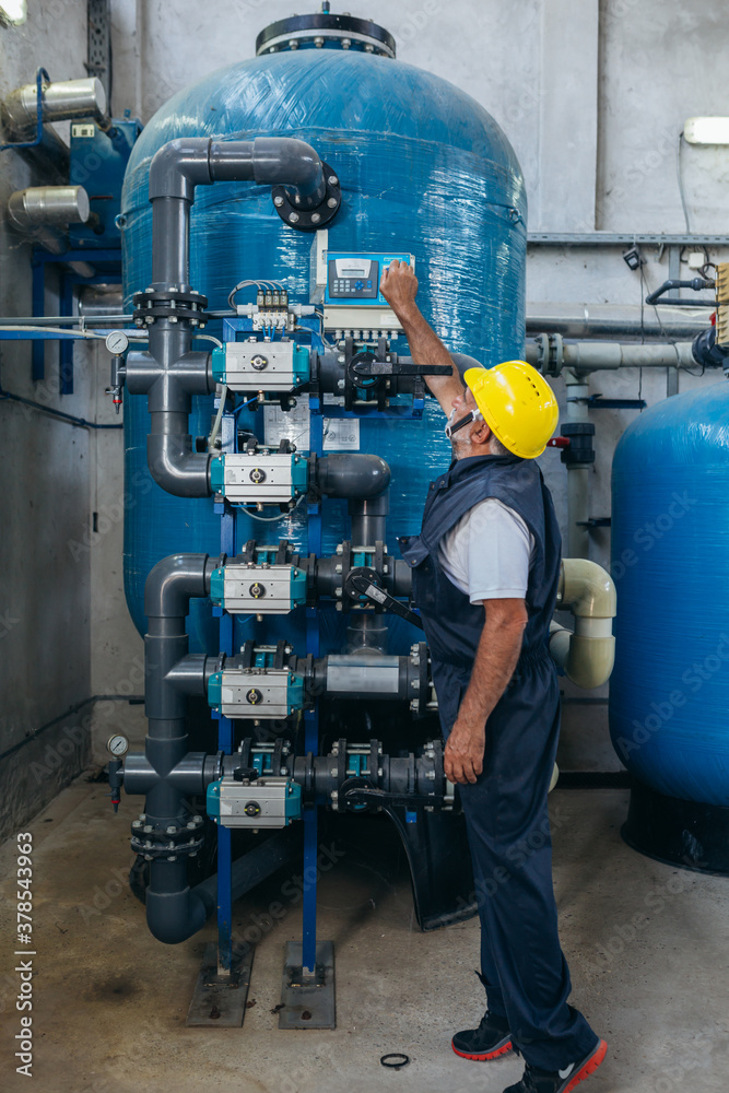 industry worker checking chemical water treatment equipment