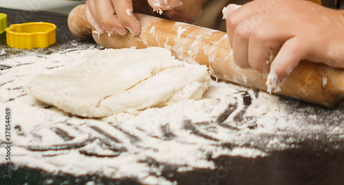 The confectioner prepares the dough, bread, cakes. Preparation and work with flour, eggs, milk and ingredients. Delicious food, recipes, cooking, gastronomy, on a dark background and wooden table.