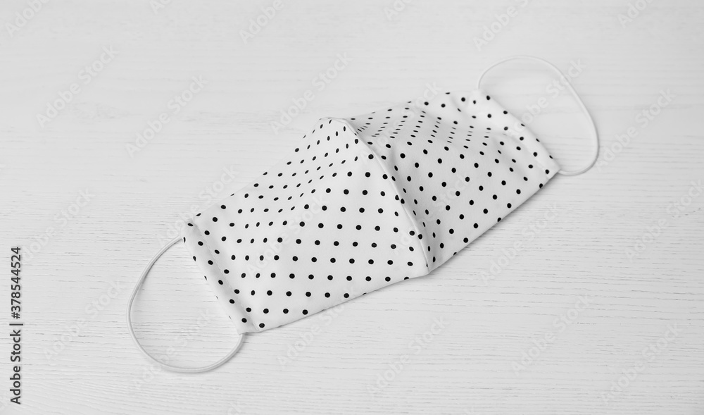 Handmade cloth mask on white wooden background. Personal protective equipment during COVID-19 pandemic