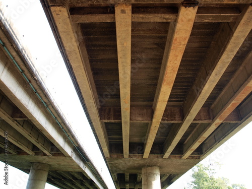 Structures and beams under the bridge on columns. A double concrete bridge in the bottom view on a white sky background. Selective focus