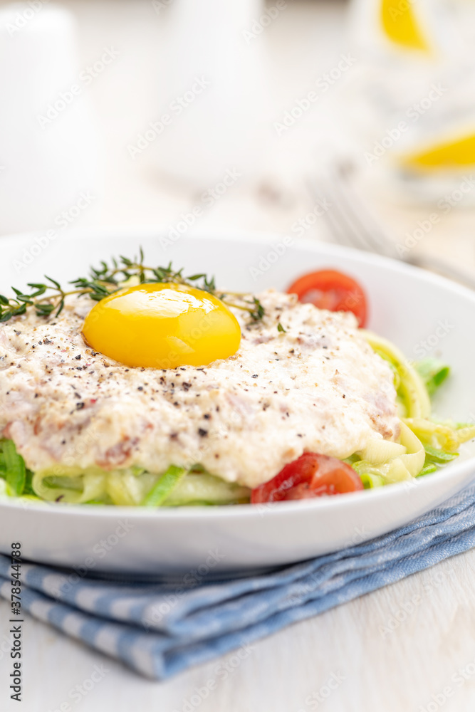 Carbonara sauce. Fried ham in heavy cream and with raw egg yolk and cherry tomatoes. Carbonara pasta made with fresh zucchini noodles. Carbonara sauce. Fried ham in heavy cream and with raw egg yolk and cherry tomatoes. Carbonara pasta made with fresh zucchini noodles.