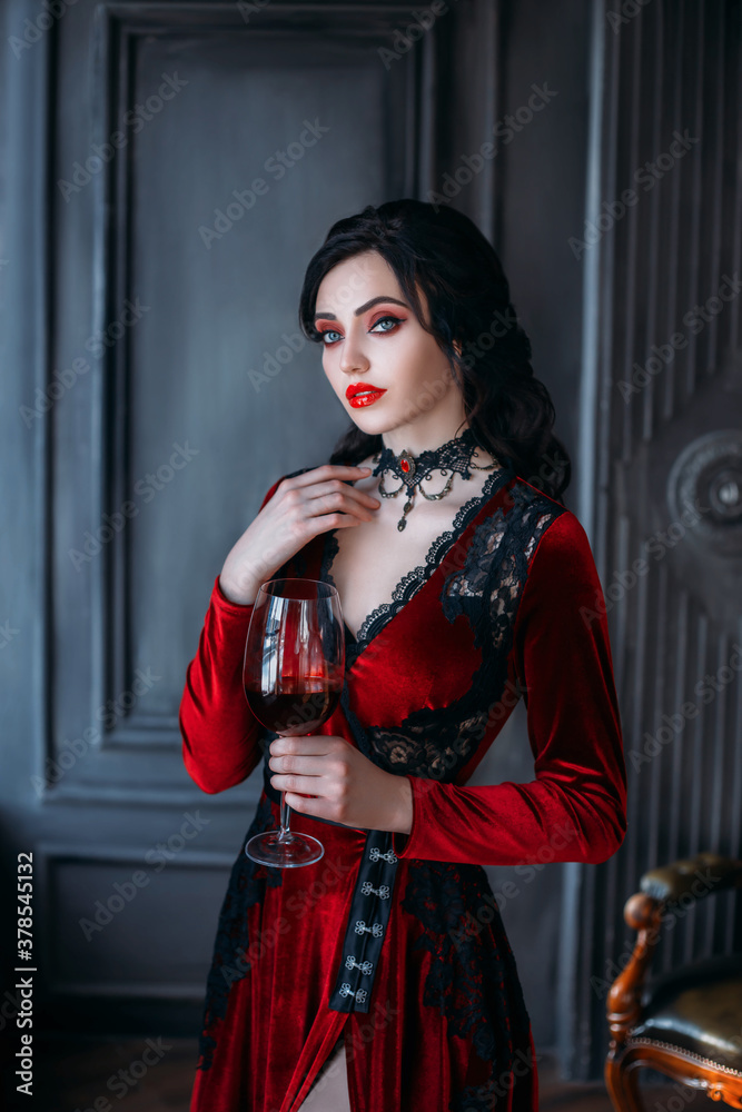 Beautiful young sexy woman vampire in medieval dark castle. Red gothic  evening dress. Black wavy hair.