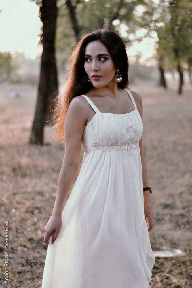 Long-haired brunette in a white dress in the woods Long-haired brunette in a white dress in the woods