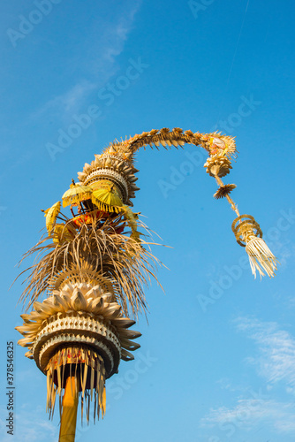balinese penjor decorating the streets during galungan and kuningan celebration with a blue sky background