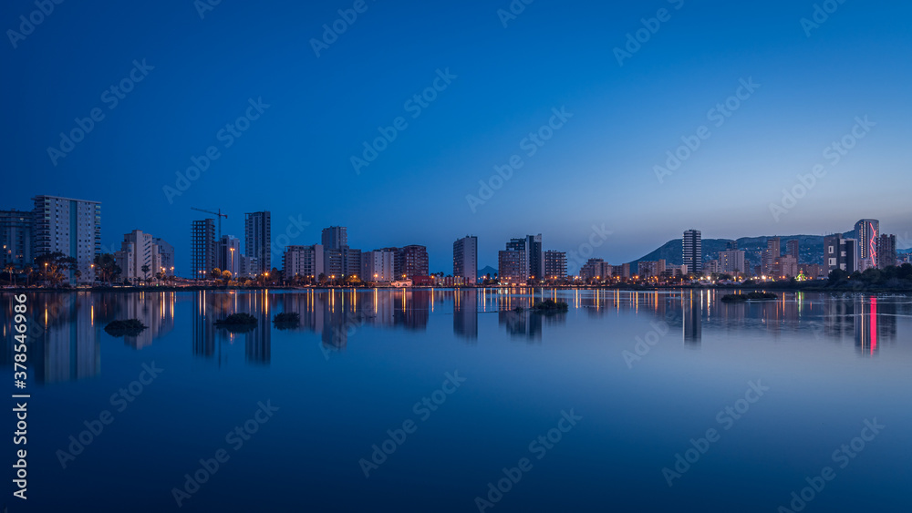 City skyline of Calpe reflected in the salt lake at dusk, Alicante, Spain
