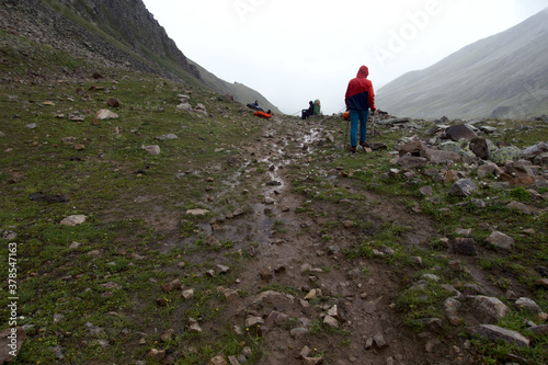  Tourists on a mountain pass in foggy and rainy weather. Mountain crossing. Caucasus. 
