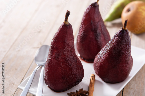 Poached pears in red wine on wooden table. Copy space 