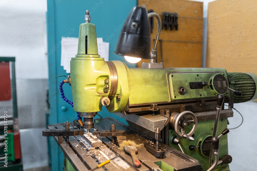 Execution of the work process on an industrial milling machine. The metal part is clamped in the collet. The cutter makes a longitudinal groove. Coolant is supplied. Metal shavings fly to the sides. Execution of the work process on an industrial milling machine. The metal part is clamped in the collet. The cutter makes a longitudinal groove. Coolant is supplied. Metal shavings fly to the sides.
