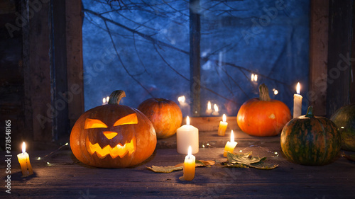 Halloween background, pumpkins and Jack-o ' - lantern next to burning candles on the background of an ominous night window