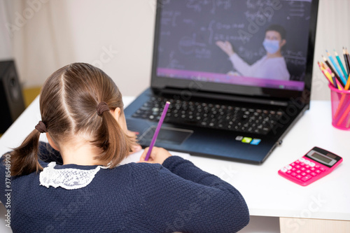 Study online with video call teacher. Young girl learn online and looking at laptop at home.Social distancing.