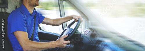 Slika na platnu transport services and logistics - young male driver in blue uniform driving a van
