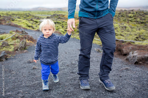 Smiling toddler child, boy, posing in front of beautiful wooly moss on a rainy day in Iceland