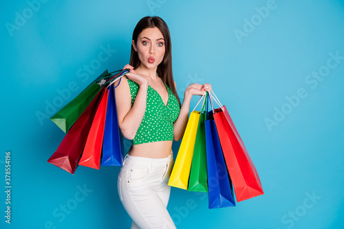 50 sales. Astonished girl make lips pouted plump hold many bags impressed wear white pants trousers tank-top isolated over blue color background
