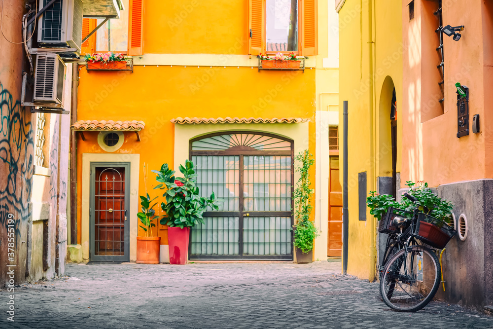 Old cozy street in Trastevere, Rome, Italy with a bicycle and yellow house.