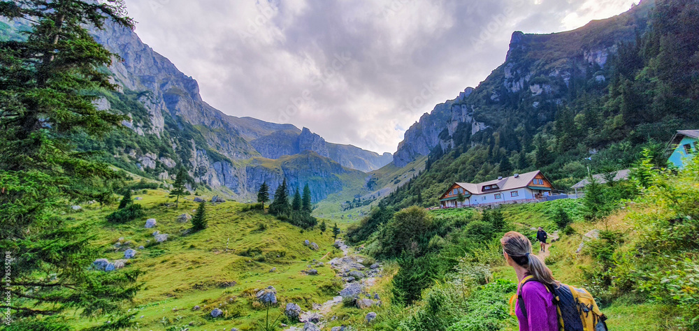 Wanderin vor Berghütte in einem Tal der rumänischen Karpaten