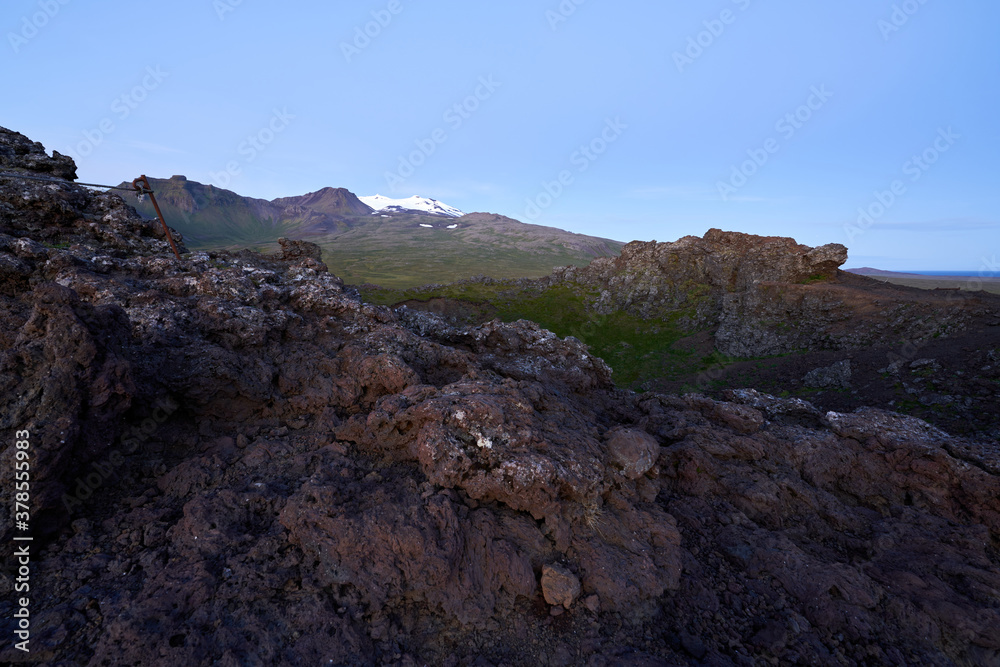 Beautiful view of saxholl crater with rocks in the foreground and with the Snæfellsjökull glacier in the distance on the island of Iceland Beautiful view of saxholl crater with rocks in the foreground and with the Snæfellsjökull glacier in the distance on the island of Iceland