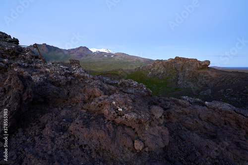 Beautiful view of saxholl crater with rocks in the foreground and with the Snæfellsjökull glacier in the distance on the island of Iceland